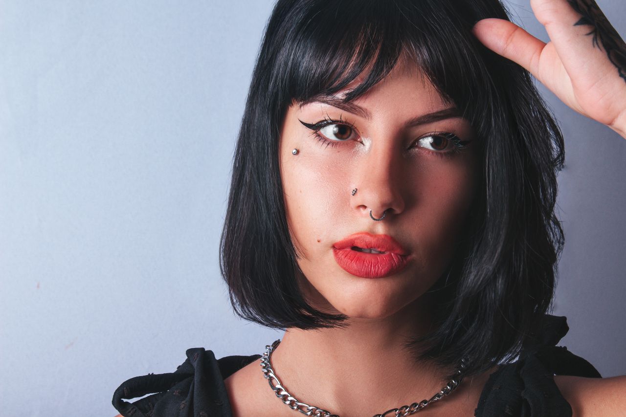 Close-up portrait of a young woman with bold makeup and piercings, showcasing her unique style.